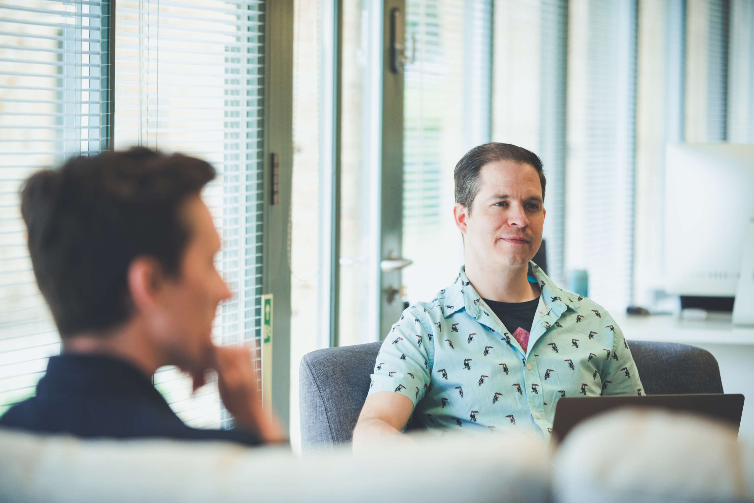 Senior designer smiles and looks at colleague during a design meeting.