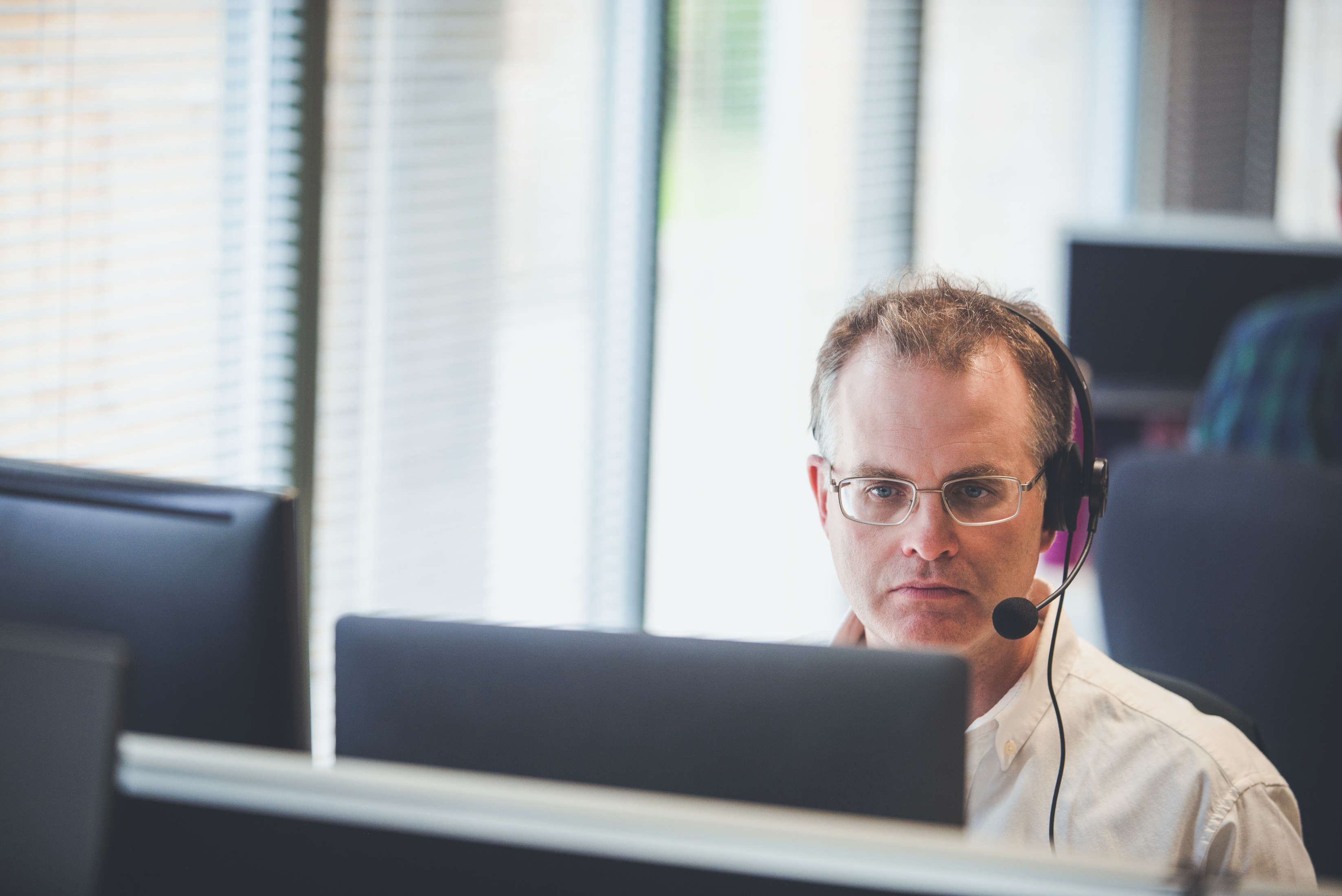 The technical director, wearing a headset looks at a screen whilst on a video call.