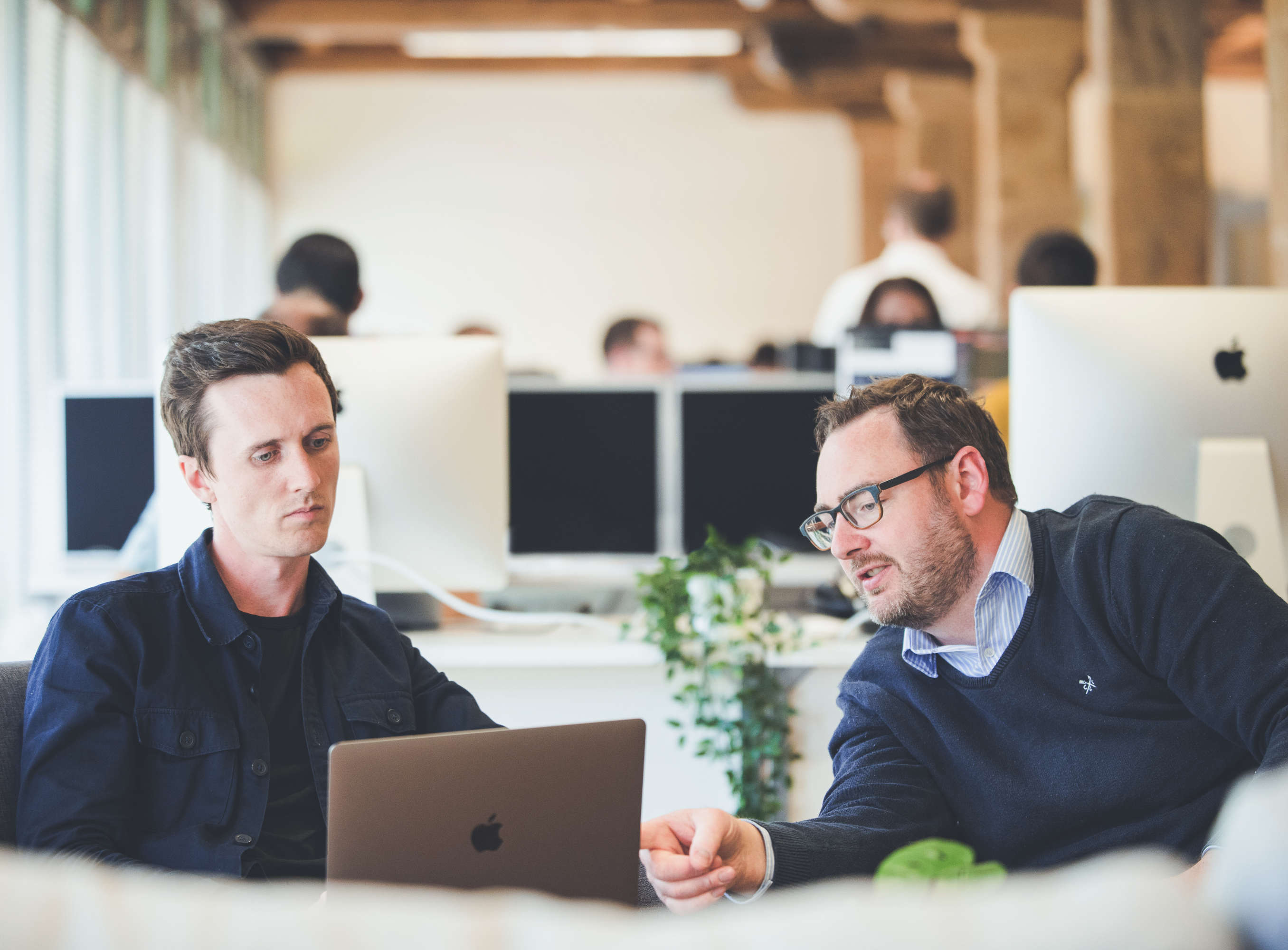 Creative director and digital strategy manager review a website during a UX review. The digital strategy manager points to an area on the laptop.