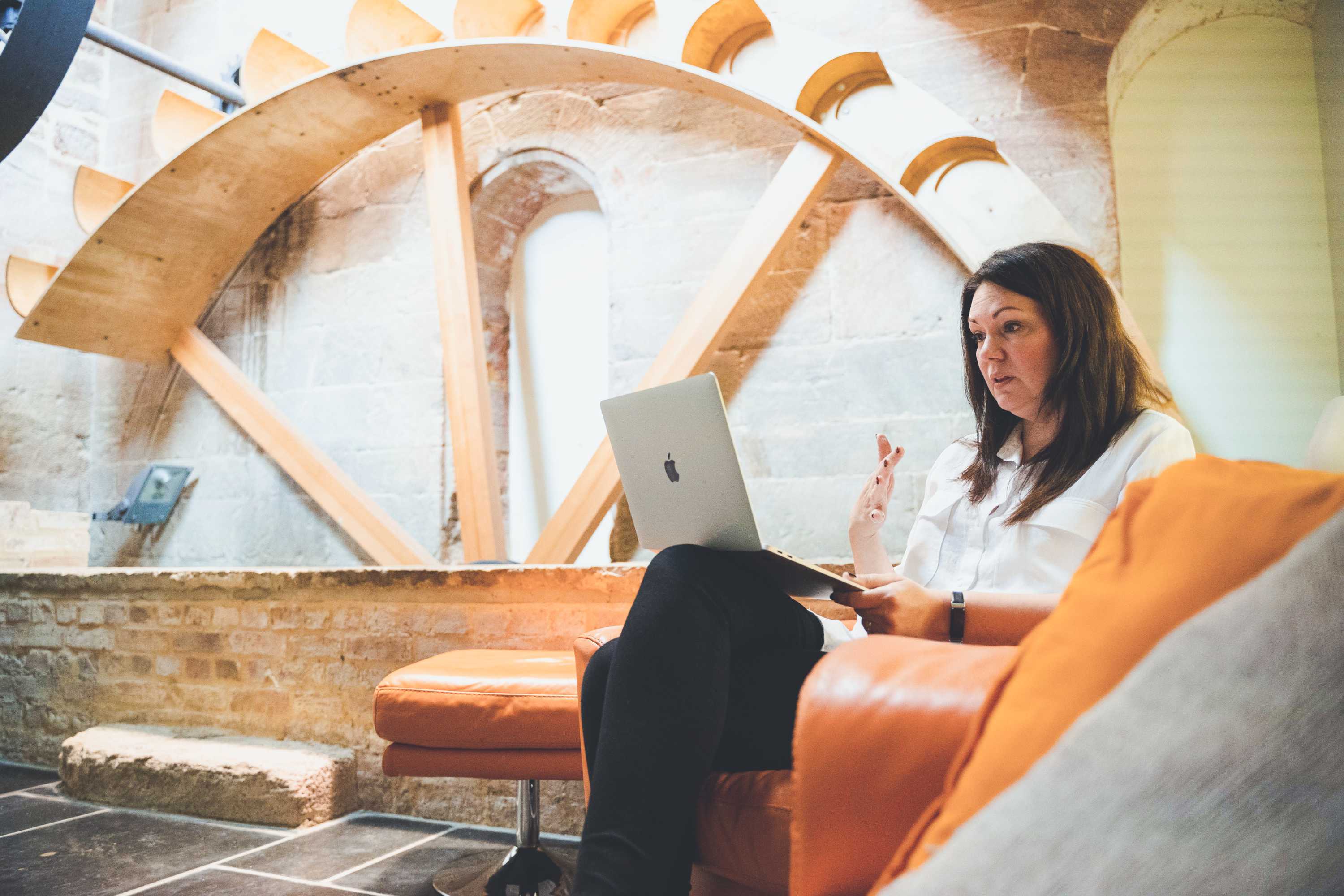 A person sitting in a barn office working on a mac computer.