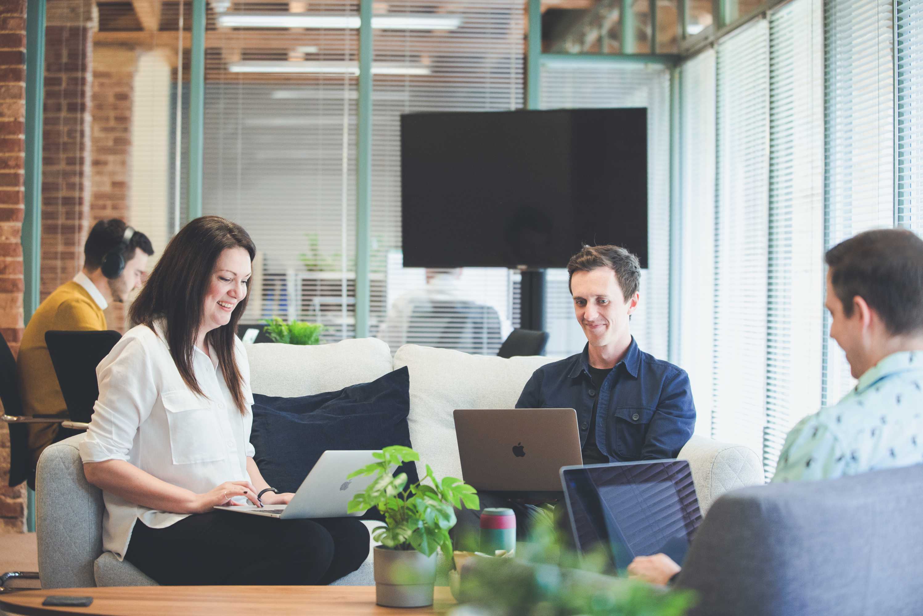 Senior designer, creative director and senior project manager sit on sofas around a coffee table and discuss the schedule.