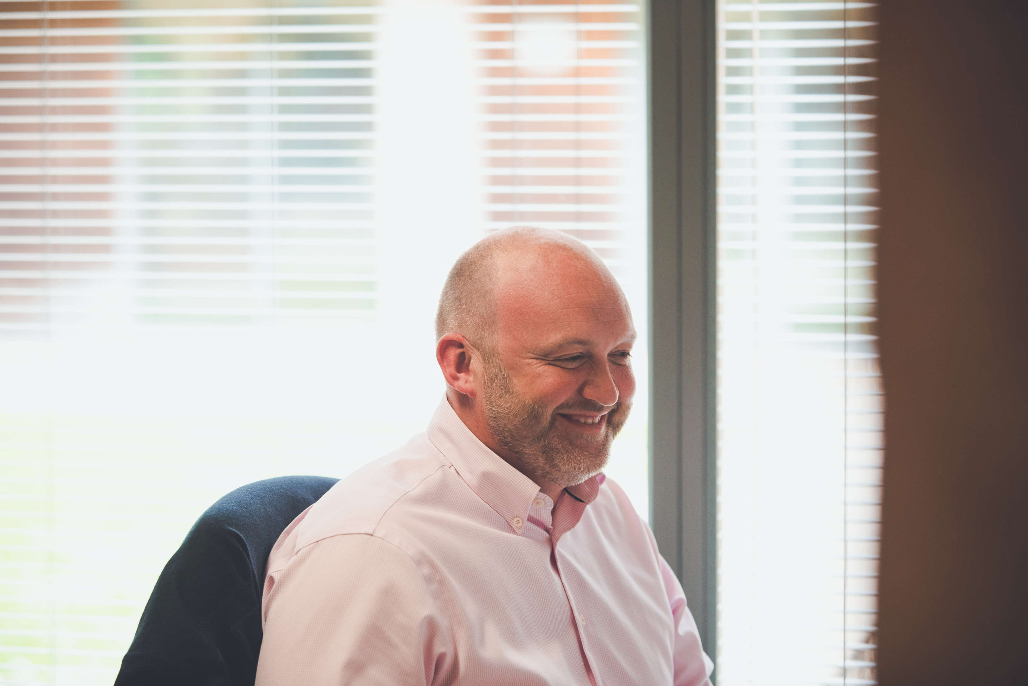 A smiling business development analyst looking at they monitor whilst chatting with a colleague.