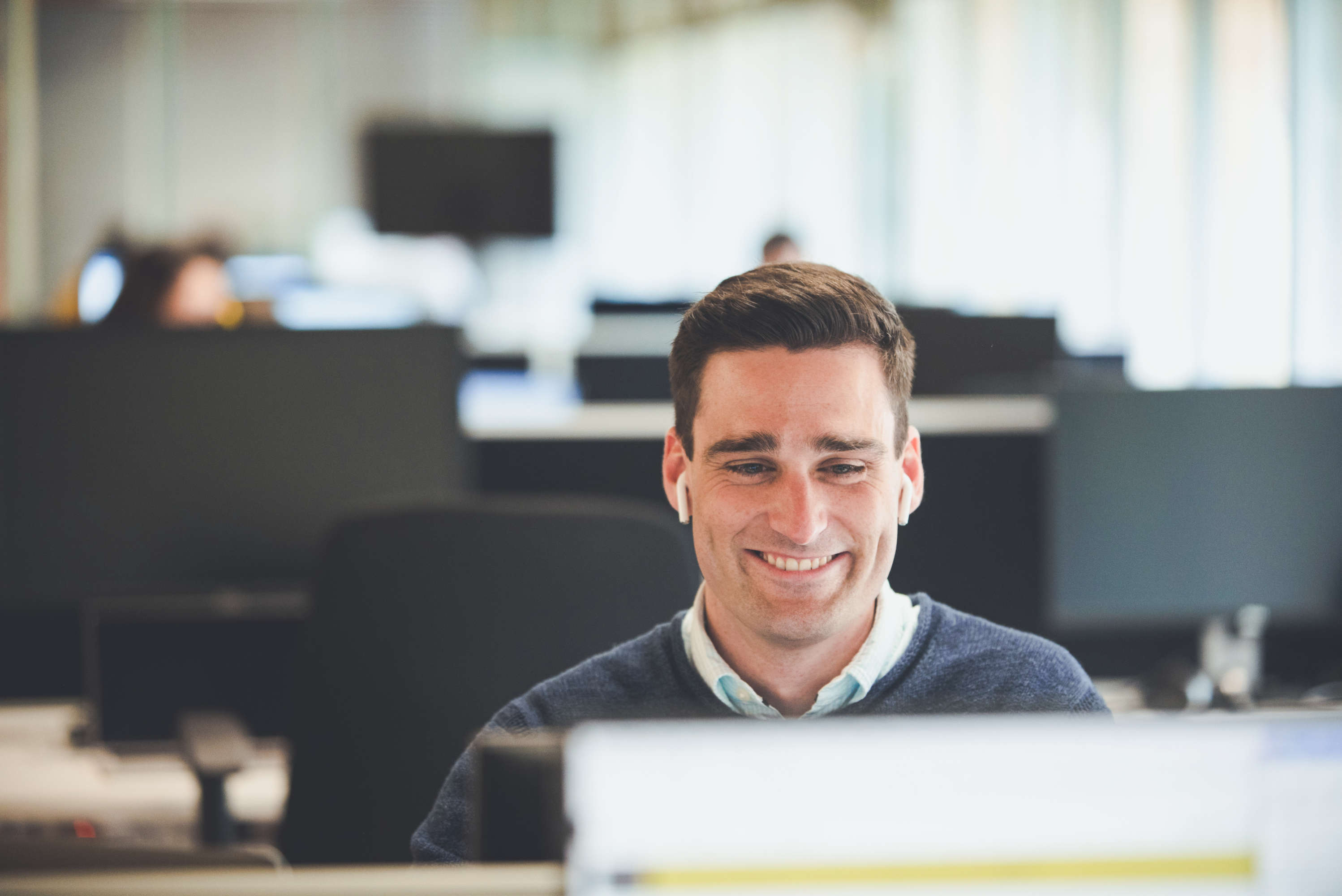 Smiling senior client manager looks at their screen whilst on a call with a client.