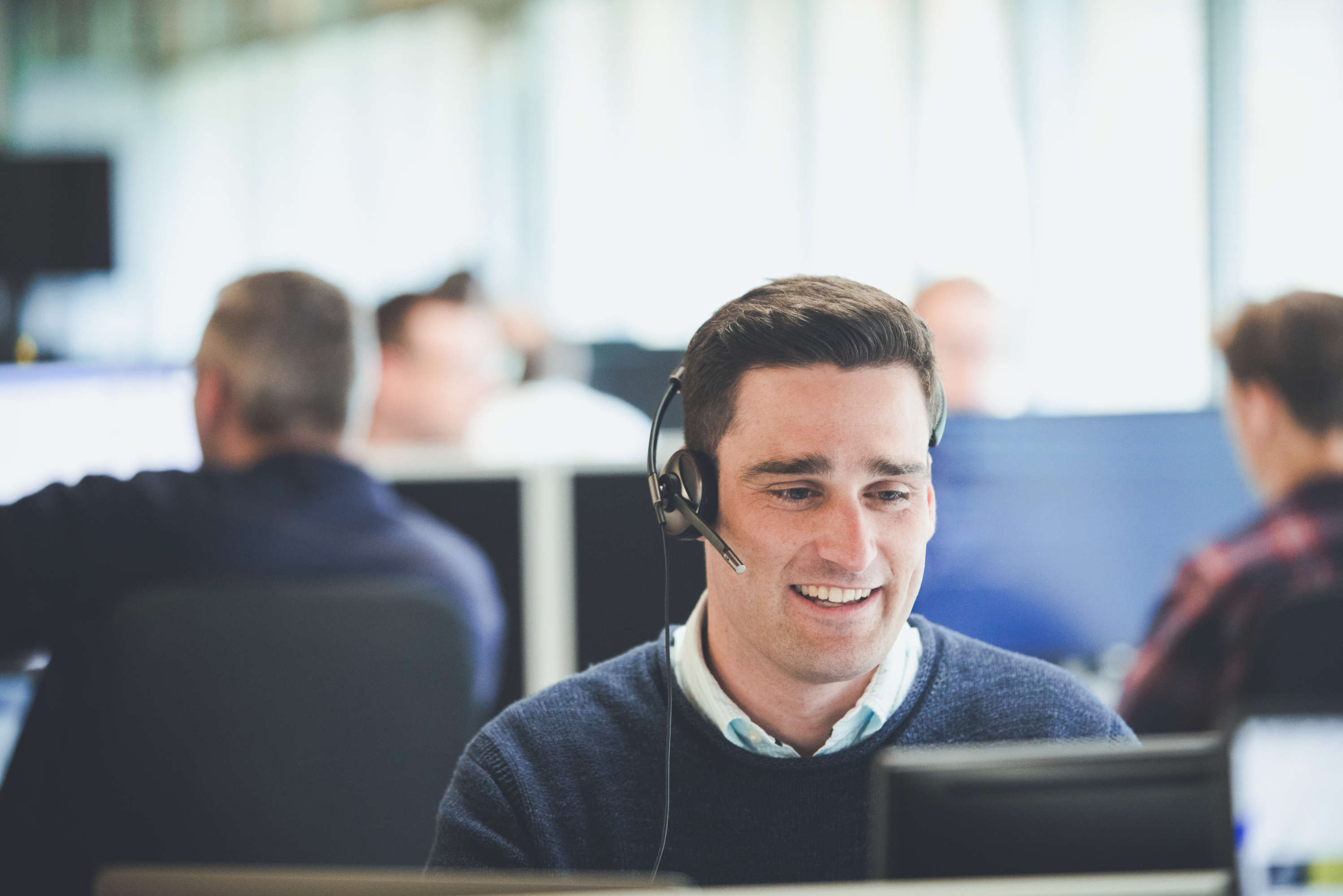 A client manager sitting at a desk, wearing a headset for a client call.