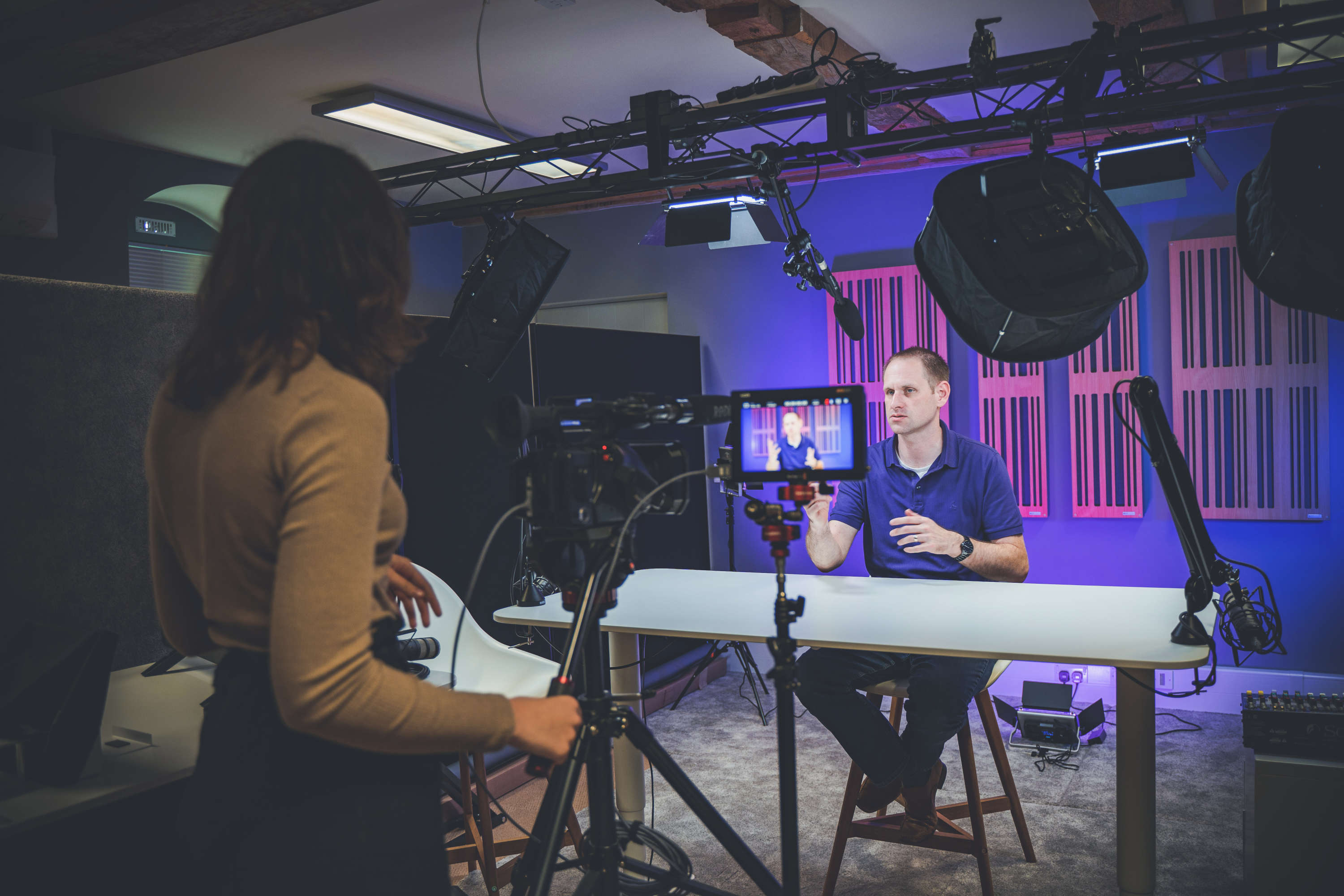 A camera operator records a presenter during filming.