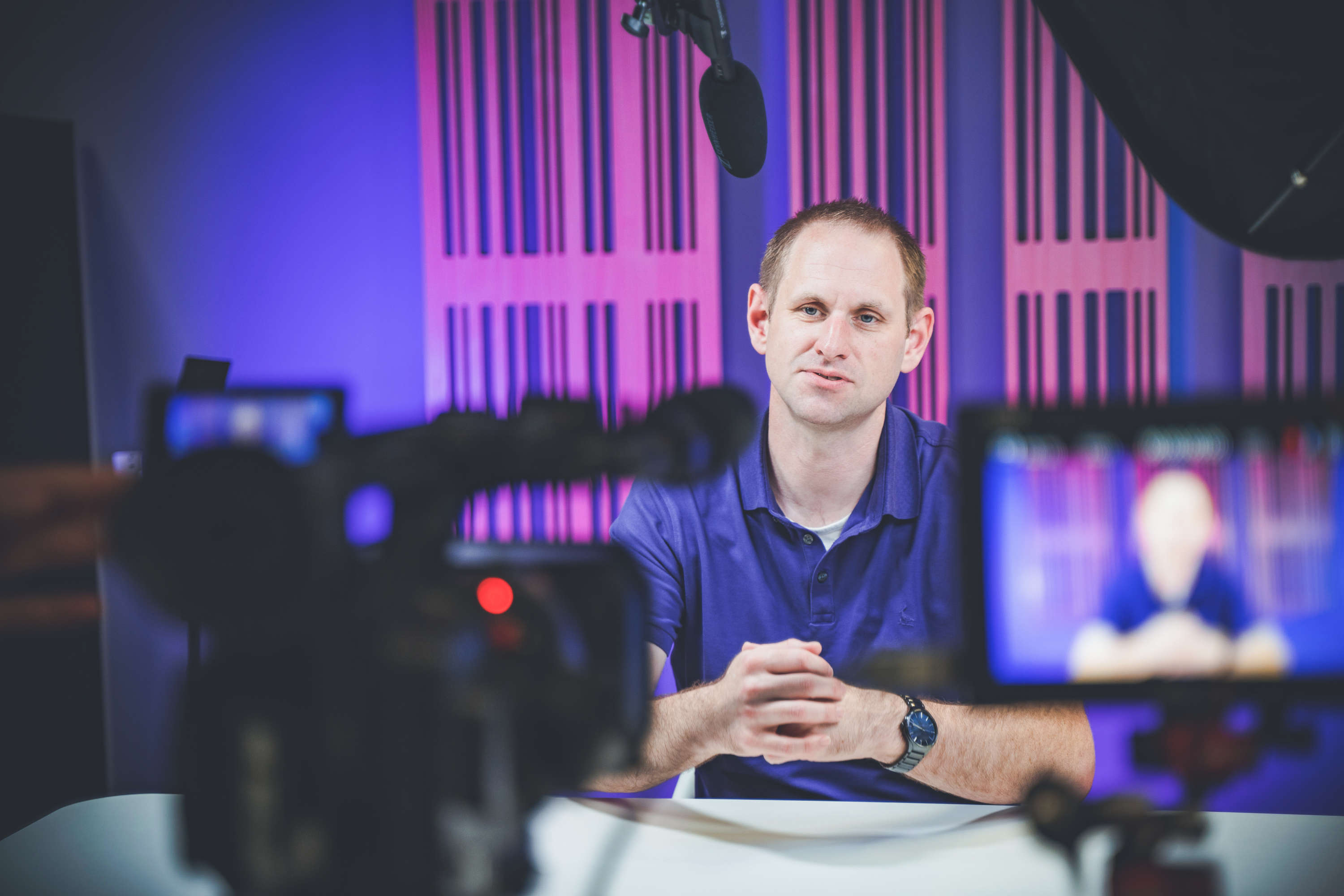 A presenter looking directly into the camera films a video opening.