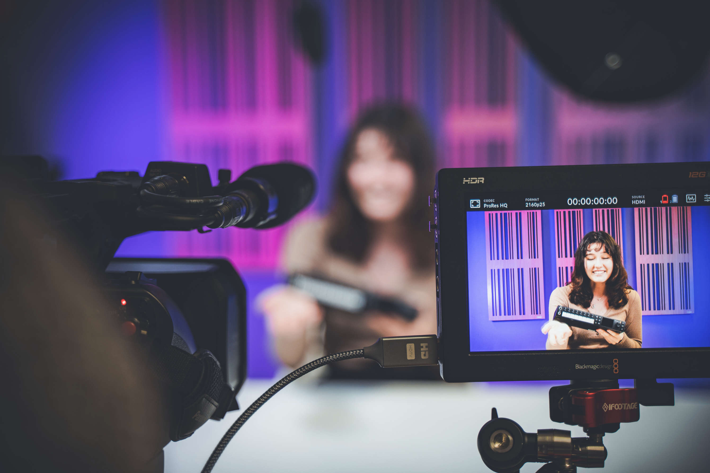 A studio camera and camera mounted monitor are used to record a presenter reviewing a product.