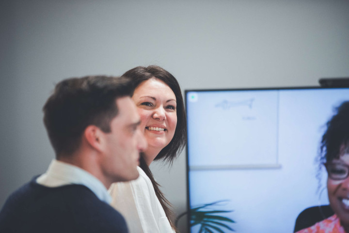 The senior project manager smiles at the camera during a video call with a colleague.