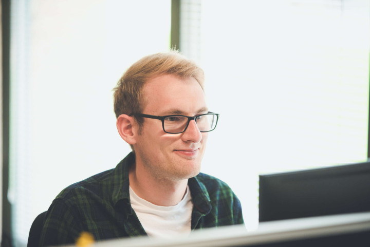 Smiling development director looks at his screen whilst working on a project.
